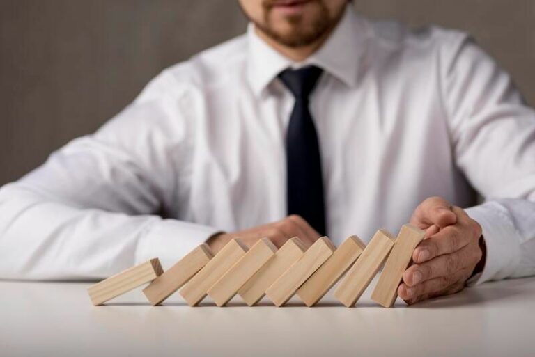 Empresario con palos de madera cayéndose representando las debilidades de una empresa